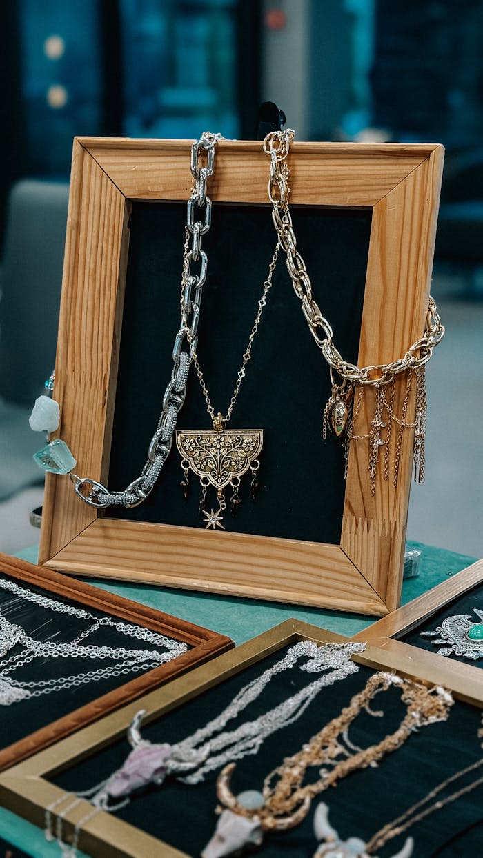 Various necklaces elegantly displayed in a wooden frame at a market.